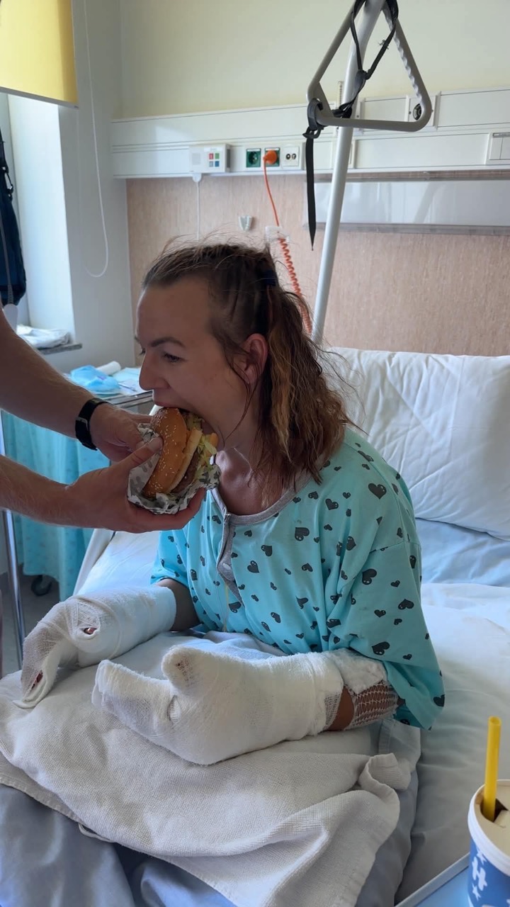 Evvu istumas haiglavoodil ja söömas lähedase abiga burgerit, mõlemad käed sidemetes.